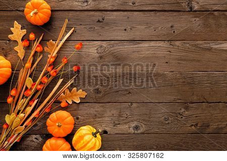 Autumn Side Border Of Pumpkins, Leaves And Chinese Lantern Branch. Top View Against A Rustic Wood Ba