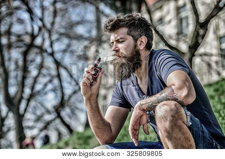 Smoking Device. Man Long Beard Relaxed With Smoking Habit. Man With Beard Breathe Out Smoke. Clouds 