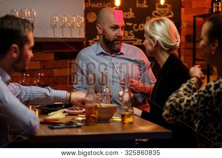 Group of friends playing sticky head game behind bar counter in a cafe