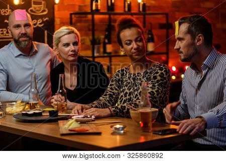 Group of friends playing sticky head game behind bar counter in a cafe