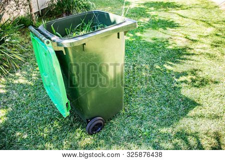 Green Bin Container Filled With Garden Waste. Spring Clean Up In The Garden. Recycling Garbage For A