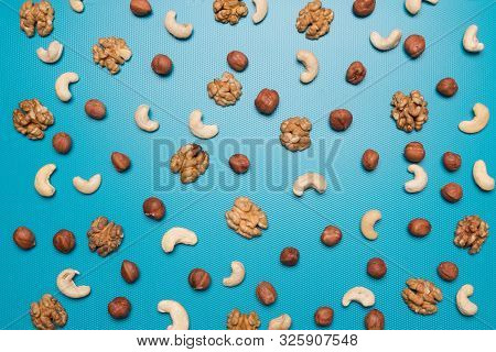 Background Of Cashews, Hazelnuts And Walnuts. Scattered Nuts On A Blue Background. Background From D