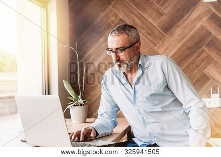 Handsome Middle Aged Man Working On Computer In A Cafe. Business, Modern Concept