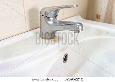 Old Dirty Washbasin With Rust Stains, Limescale And Soap Stains In The Bathroom With A Faucet, Water