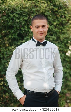 Young Man In White Shirt With Black Tie Bow Stand Outside