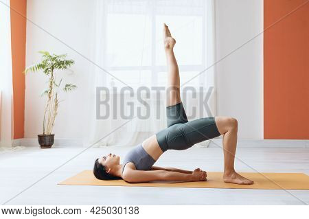 Young Woman In Leggings And Short T-shirt, Practicing Yoga, Doing Dvipada Pithasana With Leg Extende
