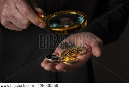 Different Crypto Currency Coins In Hand With Magnifier, Close Up. Heap Of Bitcoin And Other Cryptocu