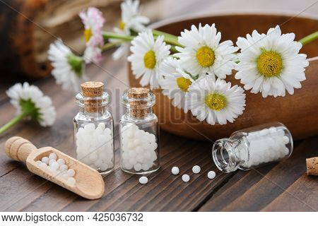 Bottles Of Homeopathy Granules. Homeopathic Remedy - Chamomilla. Daisies Flowers In Wooden Bowl. Hom