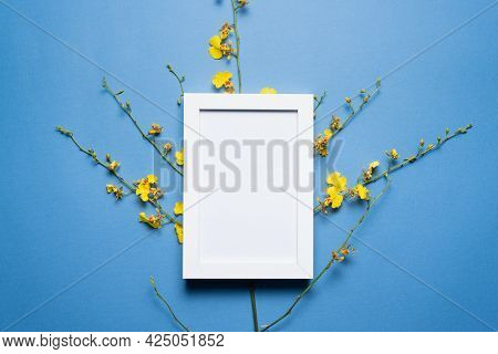 Blank Empty Picture Frame With Copy Space And Oncidium Orchid Flowers Branch On The Blue Flat Lay Ba