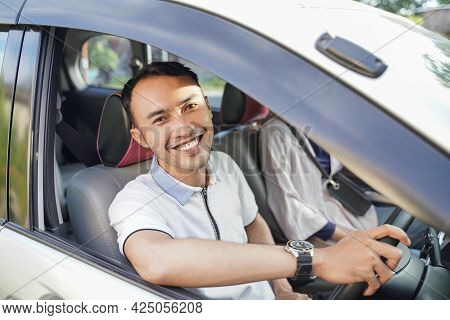 A Young Asian Man Laughing Looking At The Camera While Driving In A Car