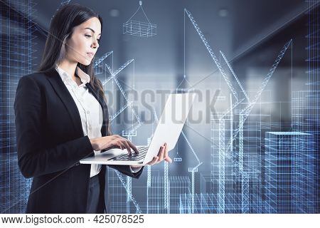 Attractive Young European Businesswoman With Laptop Standing In Blurry Office Interior With Glowing 