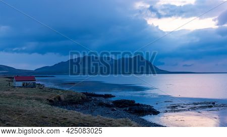 Scenic mountain landscape with dramatic sky and reflections in the lake in Iceland during night time.