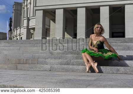 Dancing Concepts. Resting Professional Caucasian Ballet Dancer In Green Tutu Dress Posing On Stairs 