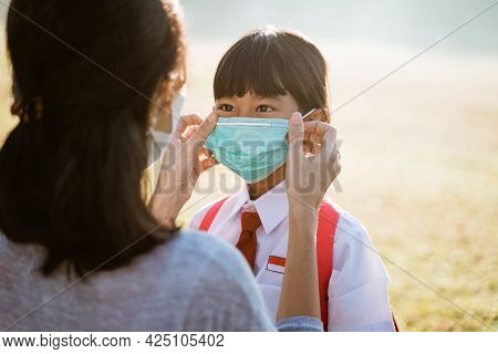 Mother Help Her Daughter To Put On The Mask Before Going To School