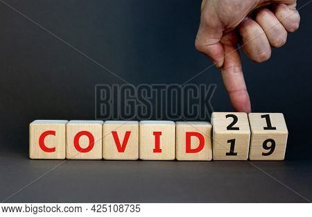 Symbol Of Covid-19 Pandemic In 2021 Year. Businessman Turns Wooden Cubes And Changes Words 'covid-19