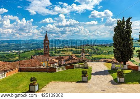 Old town of Govone overlooking green hills under beautiful blue sky with white clouds in Piedmont, Northern Italy.