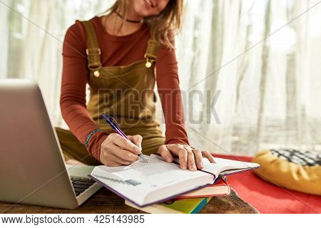 Cropped View Of A Young Woman Smiling And Making Notes, She Is Sitting In Tent On The Red Carpet Wit