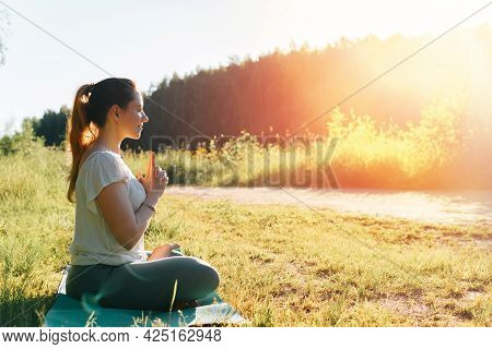Yoga In Nature. Beautiful Young Woman Practicing Yoga Asana Meditating In Lotus Position, Amazing Su