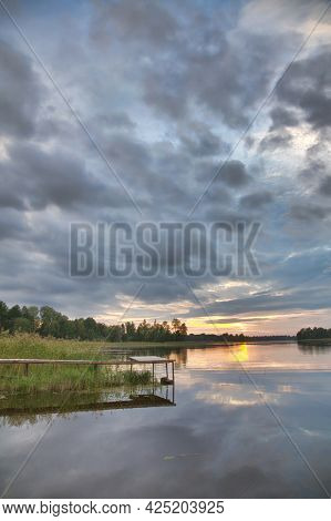 orange sunset in large clowds above river