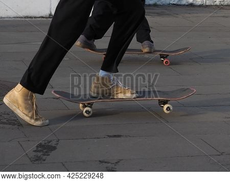 The Legs Of Two Teenagers Skateboarding On A Granite Tiled Area