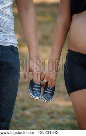 Photos Of A Pair Of Tiny Shoes In The Hands Of A Couple