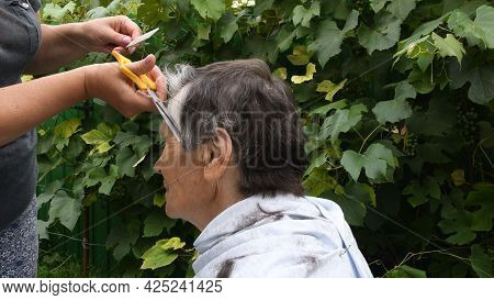 Woman Hands Trim Hair On Temple Of Senior Person With Half Gray Haired Short Haircut. Female Hands H