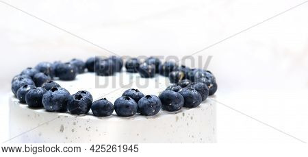 White Cake Decorated On Top Of Blueberries Stands On The Table