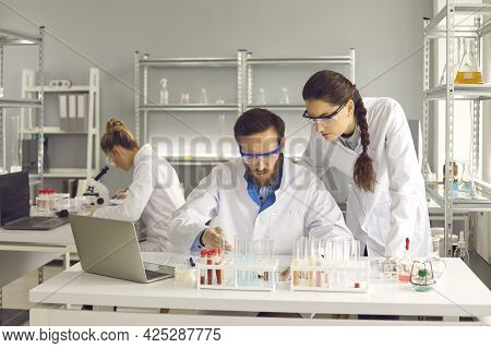Group Of Young Scientists Working In Modern Pharma Or Biotech Scientific Laboratory