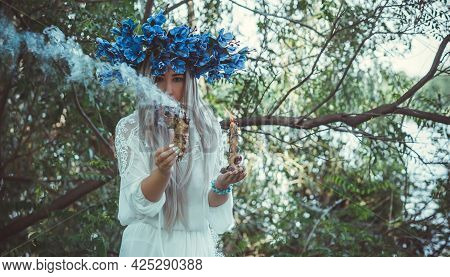 Beautiful Girl In Wreath Of Flowers In Forest. Portrait Of Young Beautiful Woman Wearing White Bride