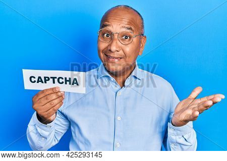 Middle age latin man holding captcha message paper celebrating achievement with happy smile and winner expression with raised hand 