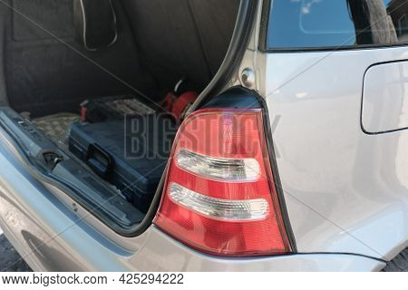 Taillight Of A Silver Hatchback Car And Open Trunk With Repair Tool Box. Summer Travel And Car Jorne