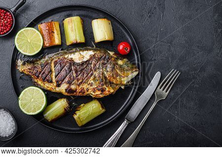Grilled Sea Bream Or Dorado Raw Fish On Black Plate With Braised Leeks  Over Textured Black Backgrou