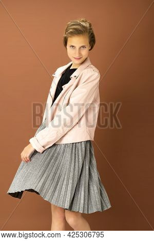 Happy Girl Whirling Against Brown Background. Joyful Attractive Brown Haired Teen Girl Dressed Pink 