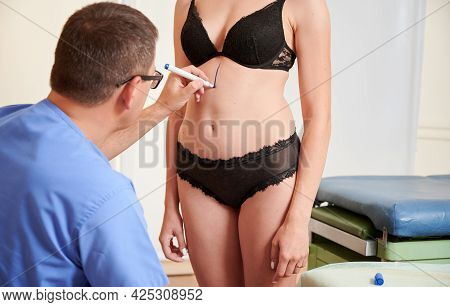 Female Patient In Black Lingerie Having Preoperative Marking Procedure In Clinic. Male Doctor Drawin