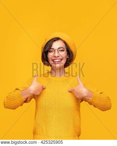 Delighted Self Confident Young Female In Yellow Knitted Sweater And Beret Pointing At Herself Saying