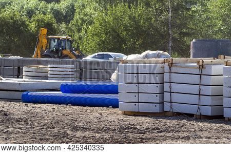 Reinforced Concrete Blocks, Well Rings, Corrugated Plastic Pipes Are Stacked At The Construction Sit