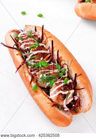Sandwich With Meatballs, Grated Carrot, Mustard And Sour Cream Sauce In Hot Dog Bun On White. Submar