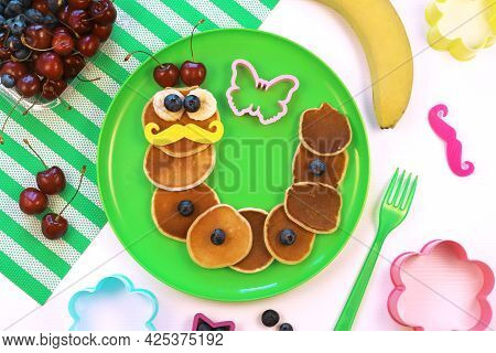 Caterpillar Or Worm Shaped Pancakes With Berries On Green Plate, Top View. Healthy Food For Children
