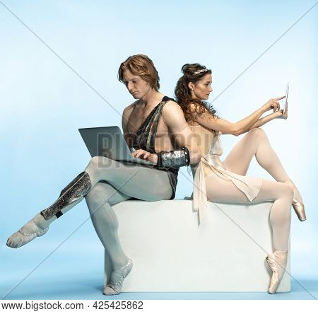 Tablet, Laptop, Digital. Young Couple Of Ballet Dancers In Ancient Rome Costums At Blue Studio.