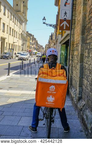 May 2021 Parma, Italy: Courier On Bike With Special Orange Backpack With Just Eat Logo Icon Close-up
