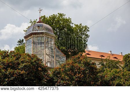 Valec, Western Bohemia, Czech Republic, 19 June 2021:  Green Trees Near Glass And Steel Greenhouse I