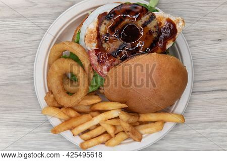 Overhead View Of Teriaki Chicken Sandwich Glazed With Sweet Sauce And Pineapple Served With Onion Ri