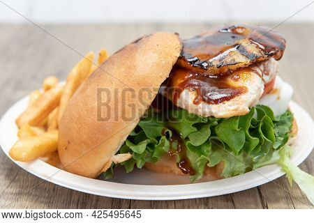 Teriaki Chicken Sandwich Glazed With Sweet Sauce And Pineapple Served With Onion Rings And French Fr