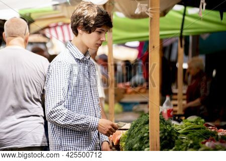 Young Pesron Choose Fresh Ripe Veggies At The Outdoor Market And Purchasing It