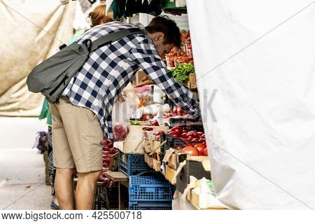 Young Pesron Choose Fresh Ripe Veggies At The Outdoor Market And Purchasing It