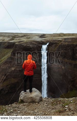 Man in a red windbreaker at the Haifoss waterfall, Iceland