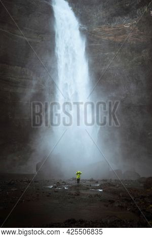 Woman in a green jacket at the Haifoss waterfall, Iceland