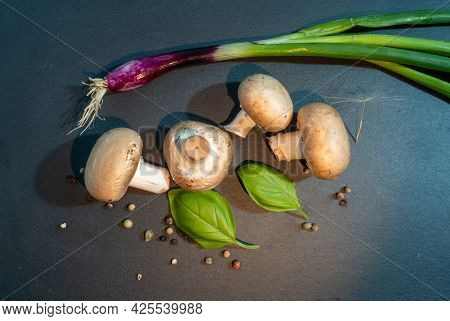 Champignons With On A Black Textured Board, Close Up.