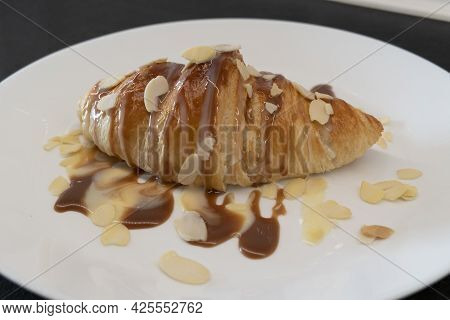 Baked Croissant With Caramel And Syrup On White Plate For Homemade Breakfast With Almond