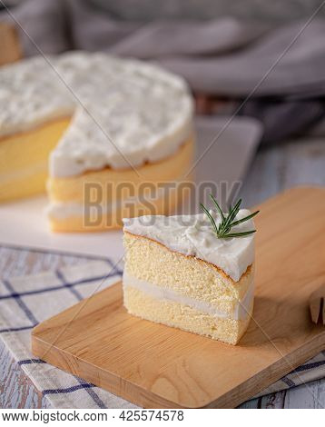 Coconut Cake - Slice Of Homemade Coconut Cake Topping With Rosemary On Wooden Board.